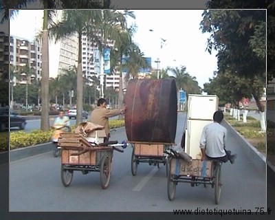 Chinois aidant un de leur collègue pour transporter un objet lourd Transporter un objet lourd avec un tricycle